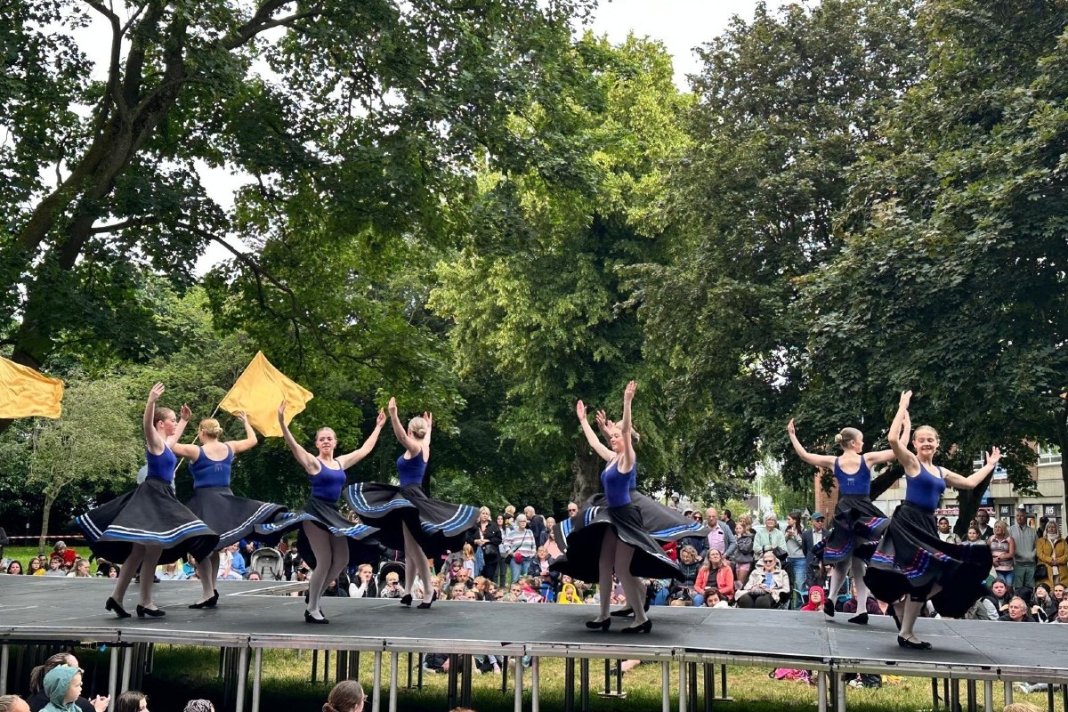 Girls in dresses dancing with flags.