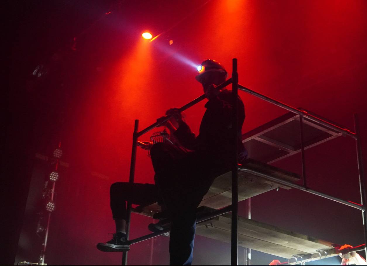Red stage with miners sitting on scaffolding