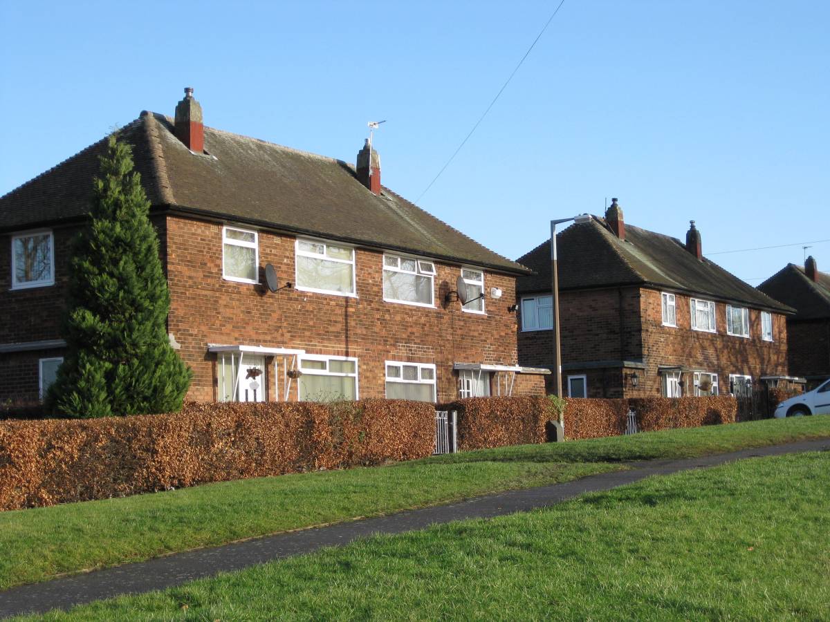 semi-detached houses on a road with a grass verge in front and a clear blue sky