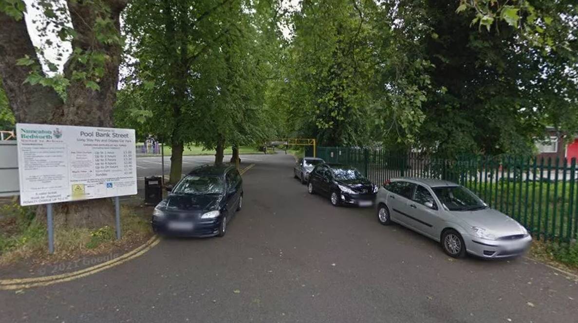 Car parked around the entrance to pool bank street car park in nuneaton in front of tall green trees